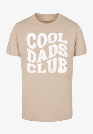 Beige tričko z bavlny s krátkými rukávy. Na přední straně se nachází velký bílý grafický nápis "COOL DADS CLUB" v tučném, opotřebovaném písmu.