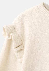 Sweter w kolorze off-white, wykonany z dzianiny, z okrągłym dekoltem i falbaniastymi detalami wzdłuż szwu na ramieniu.