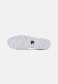 Sole de sneaker alb cu un model texturat pe talpă, având un emblemă centrală cu o stea neagră. Material din cauciuc neted și design cu vârf rotunjit.
