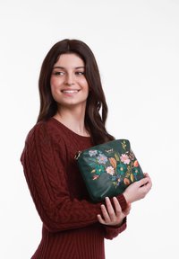 Tmavě zelená kožená taška s květinovou výšivkou v růžové, oranžové a tyrkysové; čtvercový tvar; zlaté kovové doplňky; nošena pod paží.