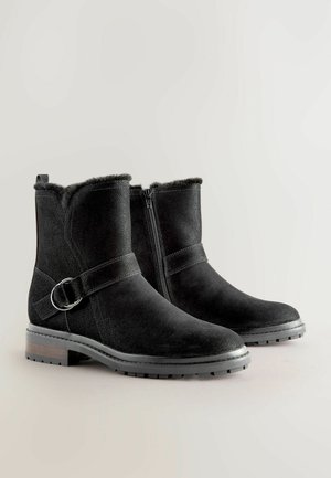 Juodos veliūro aulinės botai su užtrauktuku, dirbtiniu pūkų pamušalu, apvaliu priekiniu įdubu ir dekoratyvine sagtimi šone. Patvari tekstūruota padas.