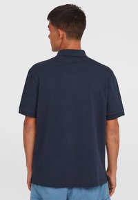 Polo à manches courtes bleu marine en tissu texturé. Dispose d'un col classique et d'un ourlet droit, avec des détails de couture visibles.