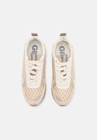 Beige sneakers with a textured mesh upper, suede accents, and round laces. Features a padded collar and a rubber sole. Logo visible inside.