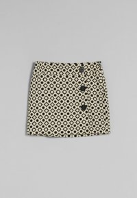 Kort beige kjol med ett svart cirkulärt mönster, prydd med fem svarta knappar framtill och en rak fåll.