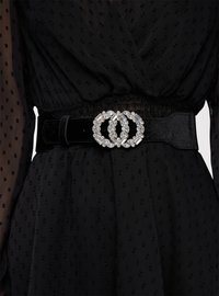 Vestito nero con texture, stretto in vita da una larga cintura in velluto nero con fibbia doppio cerchio impreziosita da pietre chiare.