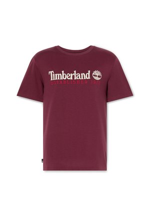Bordo puuvillapaita pyöreällä kaula-aukolla, jossa on valkoinen ja punainen "Timberland"-logo sekä "ESTABLISHED 1973"-teksti. Lyhyet hihat, yksivärinen.