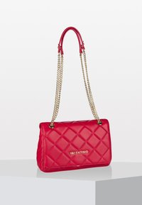 Borsa a tracolla in pelle trapuntata rossa con catene dorate, forma rettangolare e dettagli logo frontale. Texture morbida con finitura lucida.