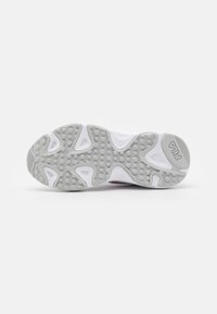 Valged sneakerite tald halli kummist haardepatterniga, millel on ümarad sõlmed ja Fila logo graveeritud kanna peal.