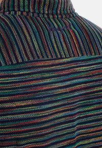 Randig skjorta i flera färger med tunna, växelvis linjer i blått, grönt, rött och gult. Texturerat tyg med krage.