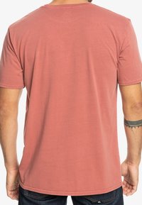 Tričko s krátkým rukávem v barvě rozjasněné růže, vyrobené z bavlny. Má kulatý výstřih, měkkou texturu a rovný lem bez viditelných grafik.