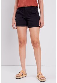 Shorts en coton noir avec poches avant, ourlet rabattu et taille mi-haute, associés à des sandales marron avec une semelle texturée.