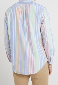 Camicia a maniche lunghe a righe multicolori, con strisce blu, verdi, rosa e gialle, polsini con bottoni e orlo arrotondato sul retro.