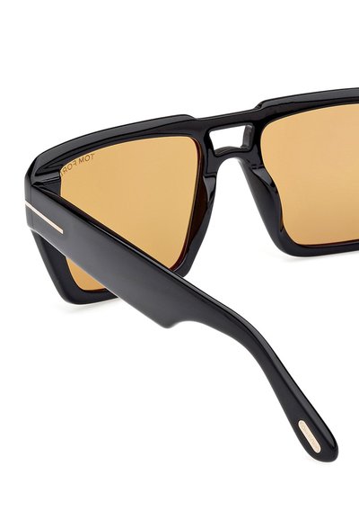 Ochelari de soare negri cu rame unghiulare, lentile de culoare brună și un accent argintiu pe sprânceană. Prezintă un design geometric și o finisare lucioasă.