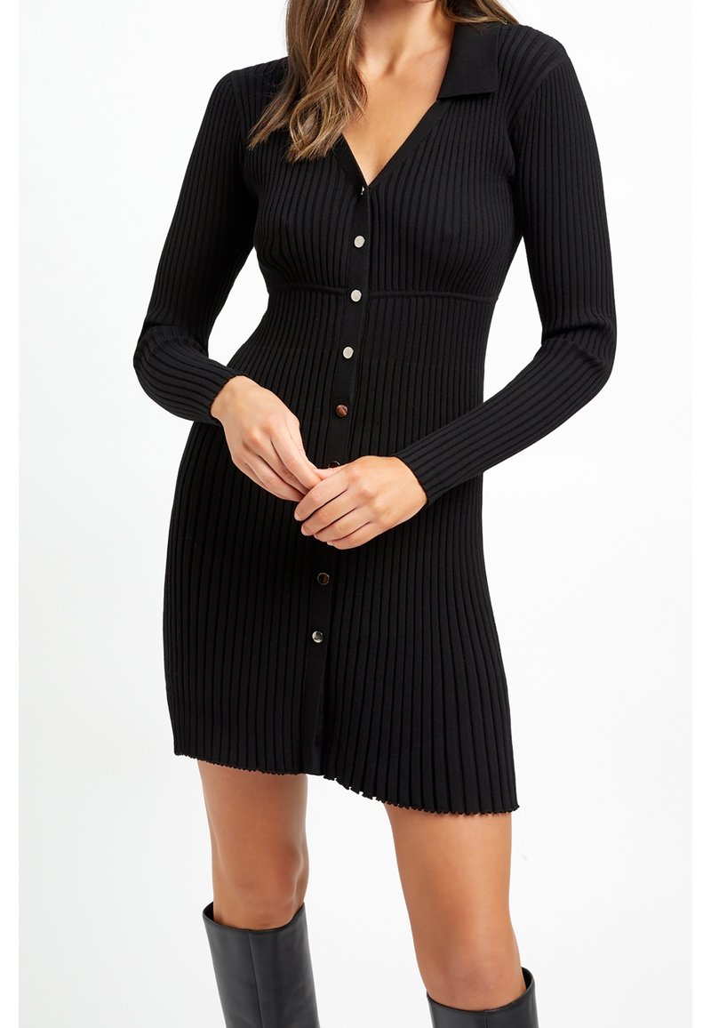 Abito nero in maglia a coste con maniche lunghe, scollo a V e chiusura frontale con bottoni. Presenta un corpetto aderente e un orlo svasato.