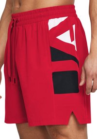Bañador rojo con una cintura elástica, cordón ajustable y paneles laterales en blanco y negro con patrones geométricos. Tejido ligero, de longitud por encima de la rodilla.