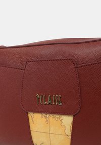 Borsa in pelle rossa textured con logo dorato, caratterizzata da un design mappale color crema come accento principale. Forma rettangolare con chiusura a ribalta.