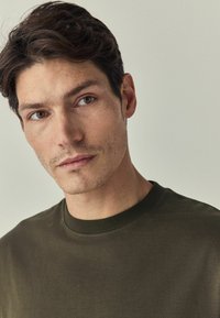 Olijfgroene crew neck t-shirt van zachte stof, met een eenvoudig ontwerp, een gladde textuur en subtiele stiksels.
