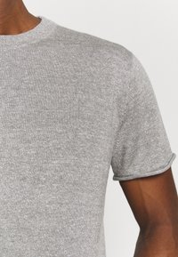 Grå kortärmad t-shirt i en texturerad bomullsblandning. Har en ribbad rund halsringning och uppvikta ärmslut.