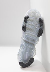 Sole boty Nike má průhlednou mezipodešev s texturovaným vzorem a tmavými gumovými akcenty. Design je zakřivený pro optimální trakci.