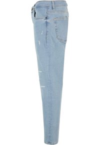 Jean slim bleu clair avec des détails légèrement usés et une poche arrière, présenté de profil sur un fond blanc.