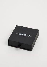 Must kast pakend, millel on libisev sahtel, peal on läikiv valge "WASTED PARIS" logo. Sile tekstuur, minimaalne disain.