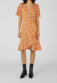 Kukallinen kietaisumekko vaaleanpunaisena, lyhyillä hihoilla ja röyhelöhelmalla. Siinä on värikäs kuvio pienistä kukista ja V-pääntie. Teksturoitu kangas.