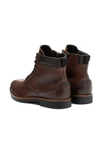 Botas de tobillo de cuero marrón con acabado texturizado, punta redonda, cierre con cordones y acentos negros contrastantes en el talón y en la lengüeta.