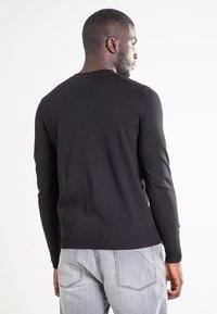 Schwarzer Strickpullover mit Rundhalsausschnitt und langen Ärmeln. Verfügt über gerippte Bündchen und Saum, glatte Textur sowie ein einfaches, figurbetontes Design.