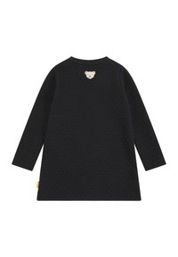 Langärmliges navy-blaues Kleid mit strukturiertem Muster, auf dem oberen Rücken mit einem Bärenkopf-Applikation und einem gelben Stoffetikett an der Seite.
