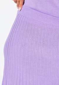 Lilac ribbattuulettu hame venyvällä vyötäröllä. Sisältää pystysuoria raitoja ja pehmeän, sileän pinnan. Lähikuva.