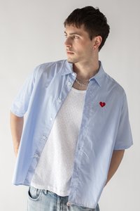 Lichtblauwe gestreepte korte mouwen shirt met knoopsluiting en rode hartborduursel aan de linkerkant, gecombineerd met een wit gestreept tanktop.
