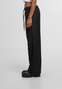 Zwarte, loszittende joggingbroek met een verstelbare tailleband, met een gladde textuur en een rechte snit.