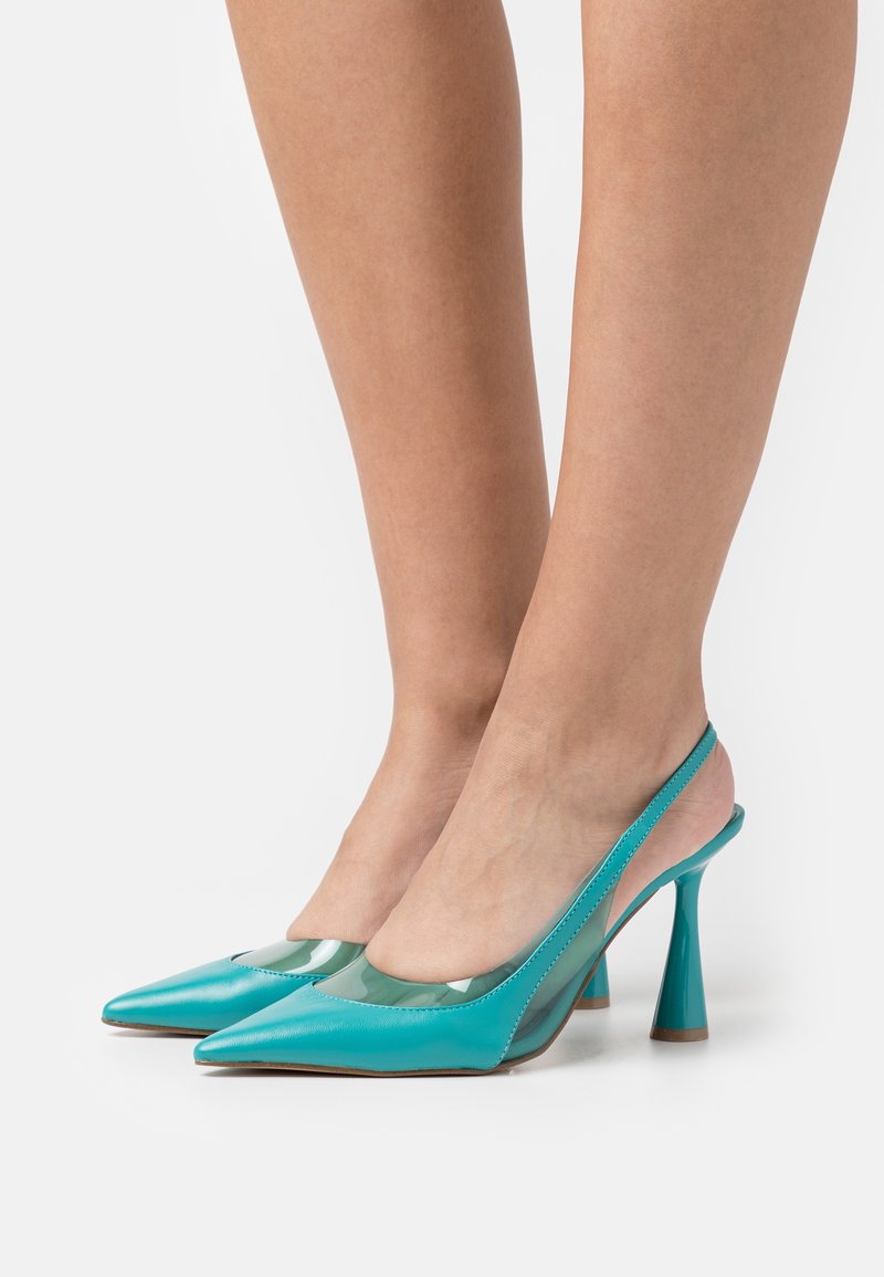 Escarpins à talons hauts trouvant dans un cuir laqué bleu sarcelle avec des panneaux latéraux transparents, un bout pointu et un talon évasé. Texture lisse avec des accents minimaux.