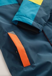 Gewatteerd jack met een mix van blauwe, gele en oranje kleuren, een gladde textuur, geribbelde manchetten en een zijzak met een accent.