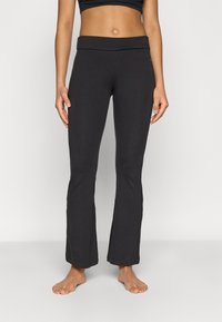 Leggings pretos flare com cós largo, feitos de material elástico, apresentando uma textura suave e sem padrões ou detalhes visíveis.