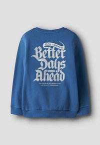 Sweat-shirt bleu avec texte blanc au style vintage au dos, indiquant "Des jours meilleurs à venir", avec des phrases plus petites au-dessus et en dessous.