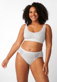 Sport bra grigio chiaro con spalline larghe, tessuto morbido e design senza cuciture. Accompagnato da slip hipster abbinati con dettagli in pizzo.