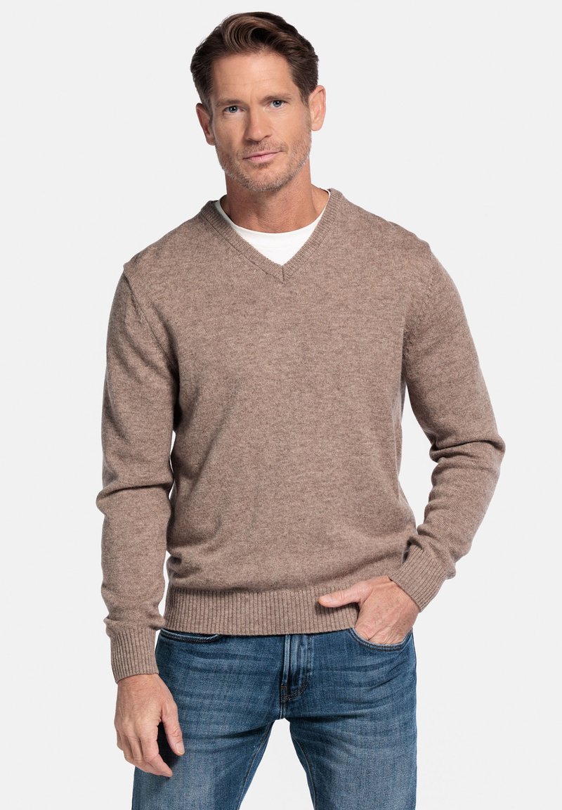 Brauner Wollpullover mit V-Ausschnitt, gerippten Bündchen und Saum, getragen über einem weißen Hemd, kombiniert mit blauen Jeans. Glatte Textur, lässiges Design.