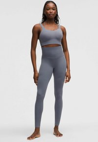 Top corto atlético gris con tirantes anchos y detalles con corte, combinado con leggings grises de cintura alta y ajuste ceñido. Textura suave en toda la prenda.