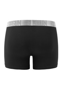 Black cotton boxer shorts featuring a soft, wide grey waistband with embossed logo. Smooth texture, fitted design, and mid-thigh length.