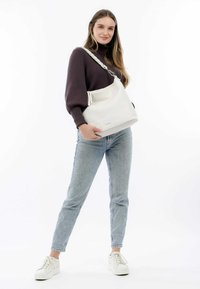 Borsa a spalla in pelle bianca con finitura testurizzata e manico intrecciato. La borsa è ampia e ha una forma arrotondata.