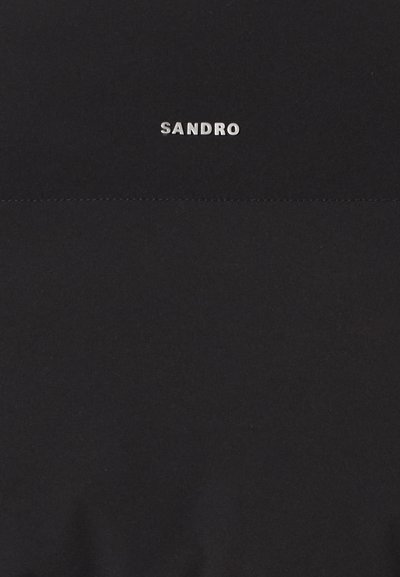 Czarna koszulka T-shirt z gładkiego materiału, z srebrnym logo "SANDRO" umieszczonym na środku w pobliżu dekoltu. Prosty wzór, bez nadruków.