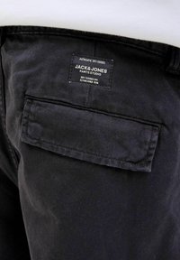 Pantaloni negri din denim, cu un buzunar posterior cu eticheta "JACK & JONES", țesătură texturată și cusături curate.