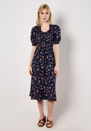 Marineblaues Blumenkleid mit kurzen Puffärmeln und einem gerafften Bund. Es besteht aus einem weichen Stoff mit kleinen rosa und grünen Blumenmustern.