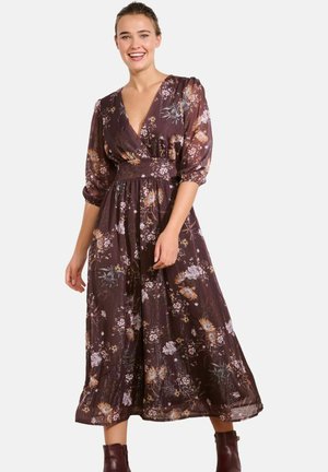 Long floral dress in dark purple with puff sleeves, v-neckline, cinched waist, and a flowing skirt. Features multicolored floral patterns.