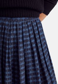 Pleated skirt in dark blue fabric with a geometric pattern of overlapping circles in darker shades. Features a fitted waistband.