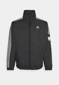 Černá tracková bunda Adidas s bílými třemi pruhy na ramenou a rukávech, předním zipem a logem Adidas na hrudi a levém rukávu.