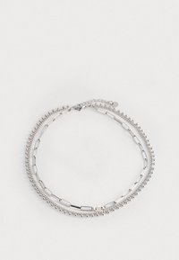 Bracciale in argento con tre fili: uno con piccole perline, uno con anelli ovali e uno con barre piatte. Presenta un'estensione a catena per la regolazione.