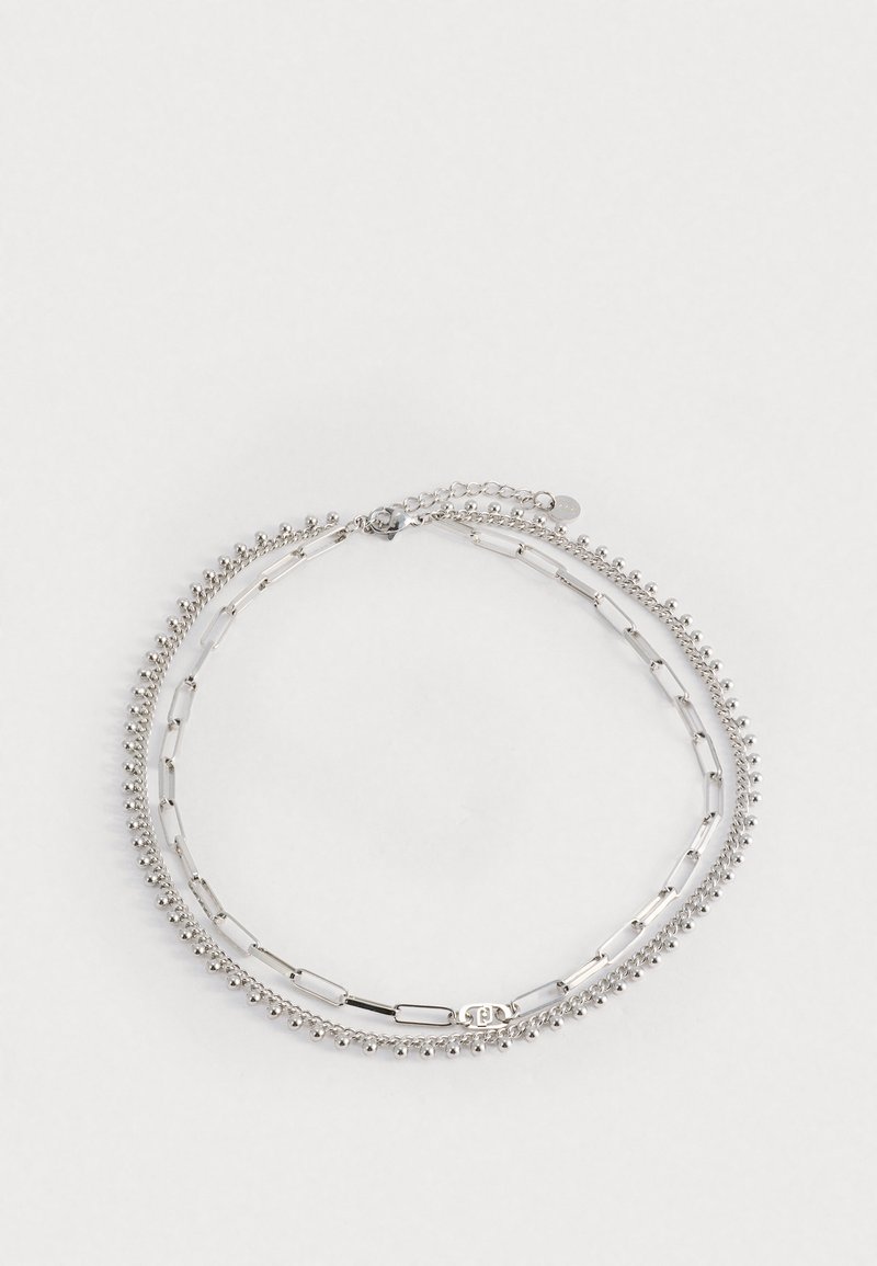 Bracciale in argento con tre fili: uno con piccole perline, uno con anelli ovali e uno con barre piatte. Presenta un'estensione a catena per la regolazione.