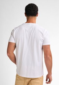 Hvid bomulds t-shirt med korte ærmer, rund hals og lige kant. Bagudsesyn viser glat stof og enkelt design.